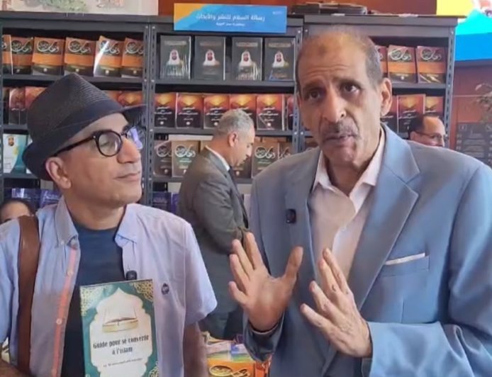 فى جناح مؤسسة رسالة السلام العالمية بمعرض مكتبة الإسكندرية الدولى للكتاب: عاطف زايد يجري حوارا مع مواطن بلجيكي للتعريف  بأهداف وأنشطة   رسالة السلام